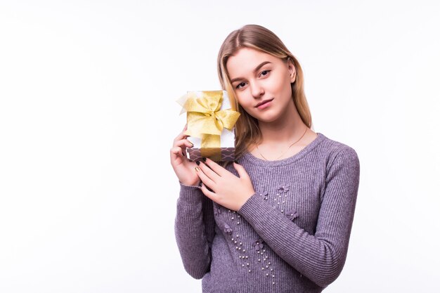 Retrato de mujer joven mantenga regalo en Navidad. Niña feliz sonriente en la pared blanca.