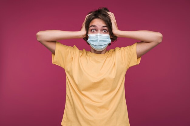 Retrato de una mujer joven con una máscara médica y mirando consternado