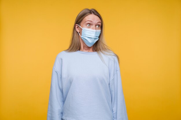 Retrato de una mujer joven con una máscara médica y mirando consternado