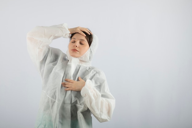 Retrato de mujer joven médico científico en bata de laboratorio defensiva posando.