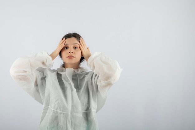 Retrato de mujer joven médico científico en bata de laboratorio defensiva posando.