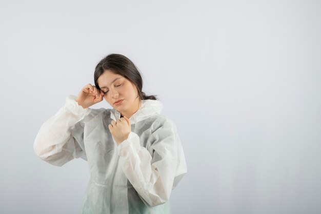 Retrato de mujer joven médico científico en bata de laboratorio defensiva posando.