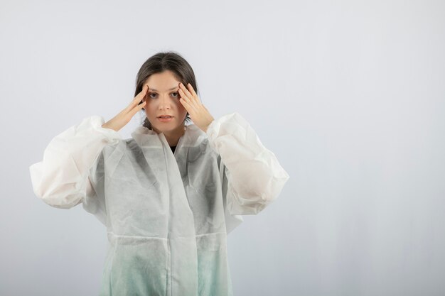 Retrato de mujer joven médico científico en bata de laboratorio defensiva posando.