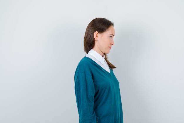 Retrato de mujer joven mirando al frente en suéter sobre camisa blanca y mirando enfocado