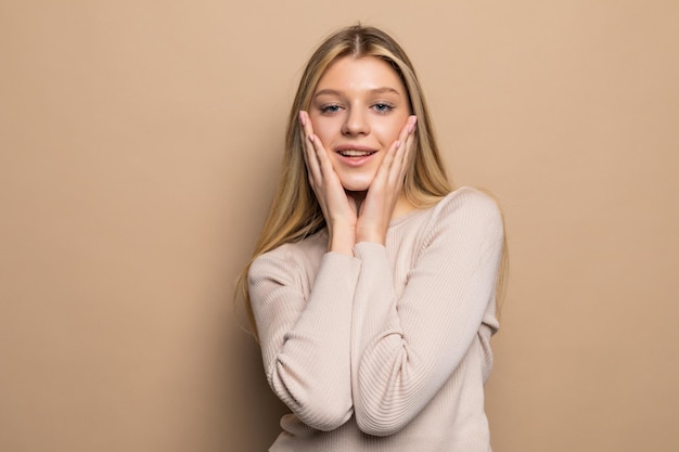 Retrato de una mujer joven mirando sorprendido en la pared beige