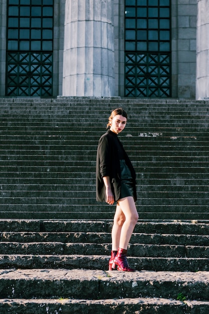 Retrato de una mujer joven de moda de pie en la escalera