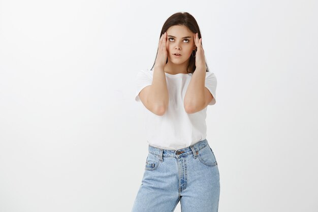 Retrato de mujer joven molesta posando contra la pared blanca