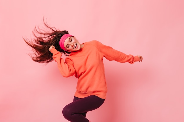 Foto gratuita retrato de mujer joven morena haciendo fitness en pared rosa