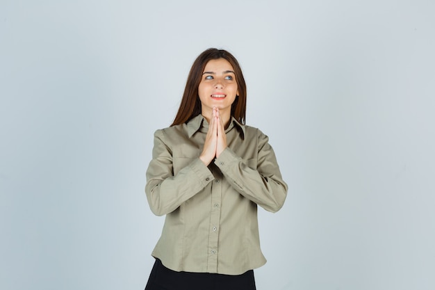 Retrato de mujer joven mostrando gesto de namaste en camisa