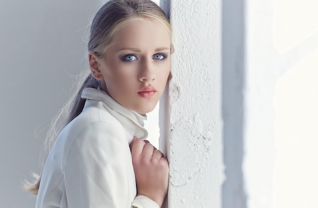 Retrato de mujer joven con ojos azules en ropa blanca.