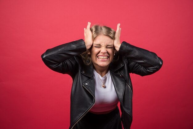 Retrato de mujer joven con los ojos cerrados sosteniendo su cabeza desde ambos lados con las dos manos