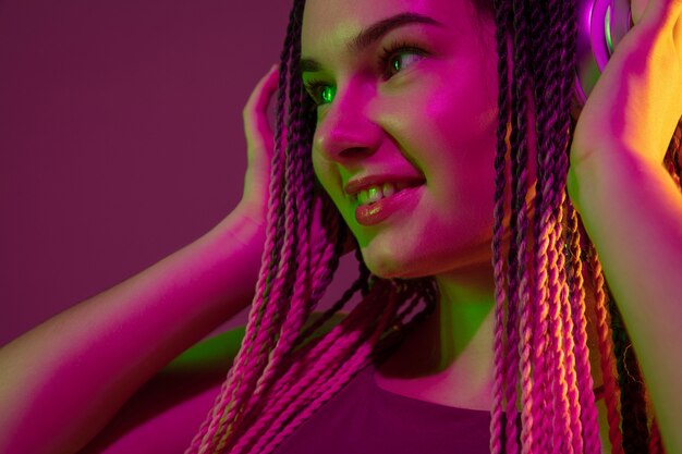 Retrato de mujer joven en pared rosa con auriculares