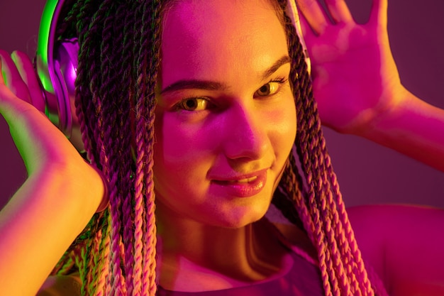 Foto gratuita retrato de mujer joven en pared rosa con auriculares