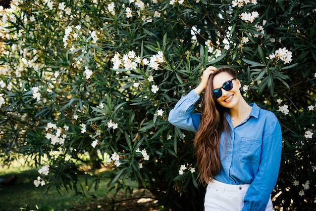 Foto gratuita retrato de mujer joven con pecas y cabello rizado, contra el fondo del parque de verano verde, hojas verdes. belleza natural.