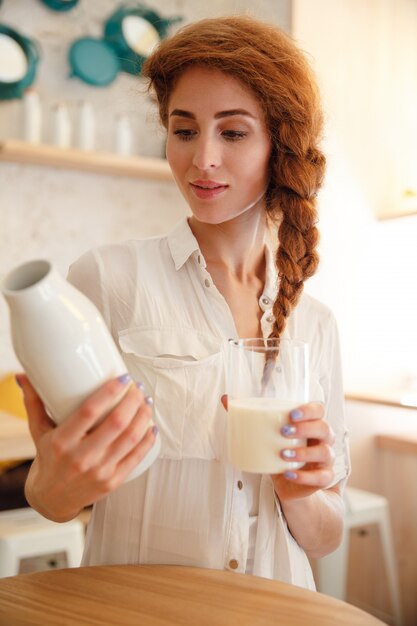 Retrato de una mujer joven pelirroja sosteniendo la botella con leche