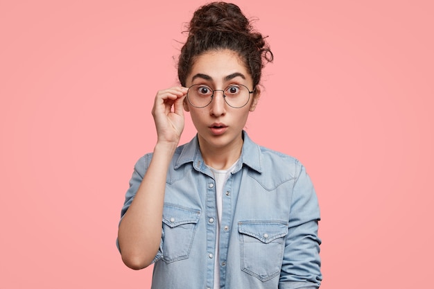 Foto gratuita retrato, de, mujer joven, con, pelo recogido, y, llevando, camisa vaquera