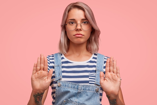 Foto gratuita retrato, de, mujer joven, con, pelo teñido, llevando, overoles