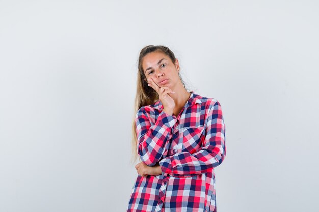 Retrato de mujer joven de pie en pose de pensamiento en camisa casual y mirando sensible vista frontal