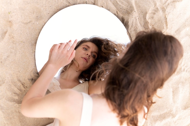 Foto gratuita retrato de mujer joven posando con confianza al aire libre con un espejo redondo