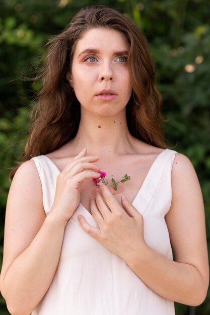 Retrato de mujer joven posando con confianza al aire libre con flores