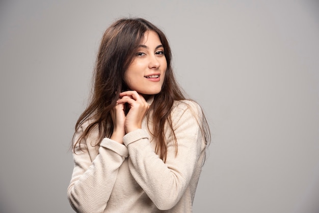 Retrato de una mujer joven posando sobre una pared gris.