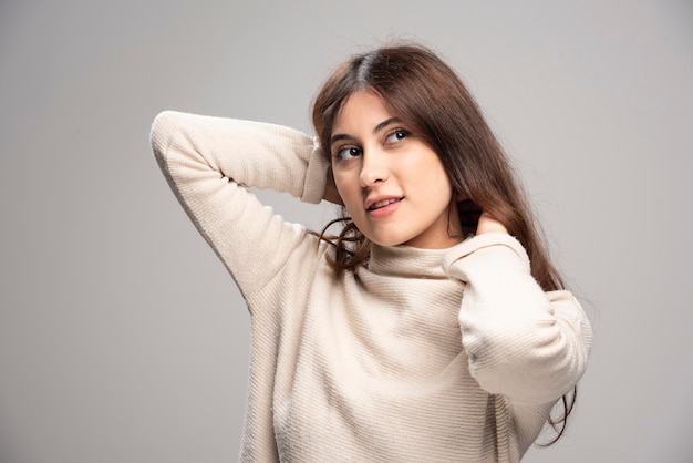 Retrato de una mujer joven posando sobre una pared gris.