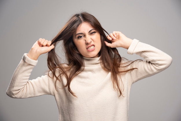 Retrato de una mujer joven posando y sosteniendo el cabello.