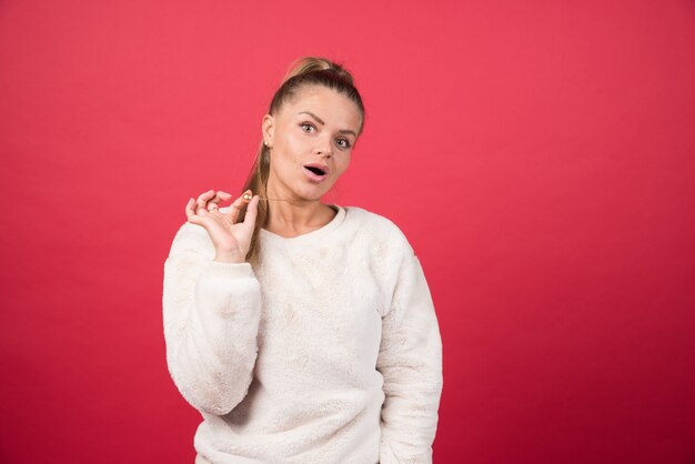 Retrato, de, un, mujer joven, posición, y, posar, en, un, pared roja