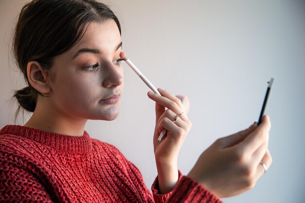 Retrato de una mujer joven el proceso de maquillarse con pinceles