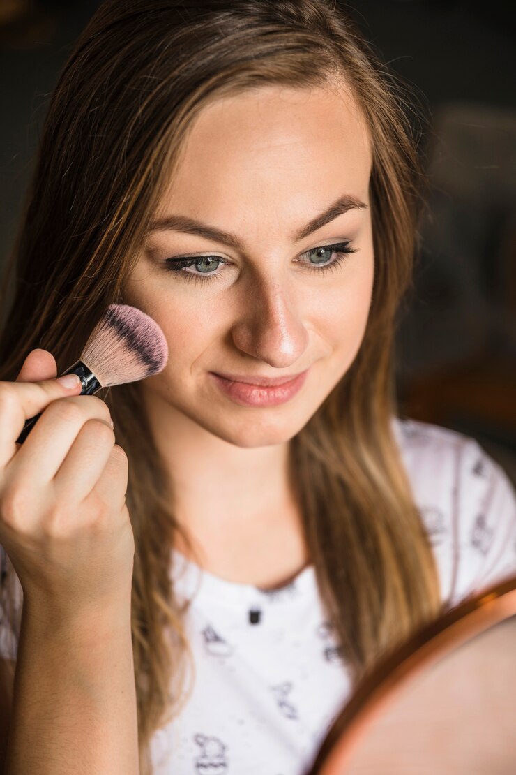 Foto gratuito retrato de una mujer joven que aplica colorete en su cara