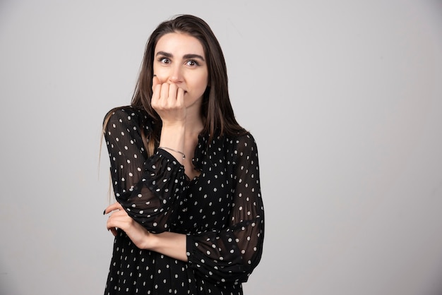 Foto gratuita retrato de mujer joven que cubre la boca detrás de los nudillos.