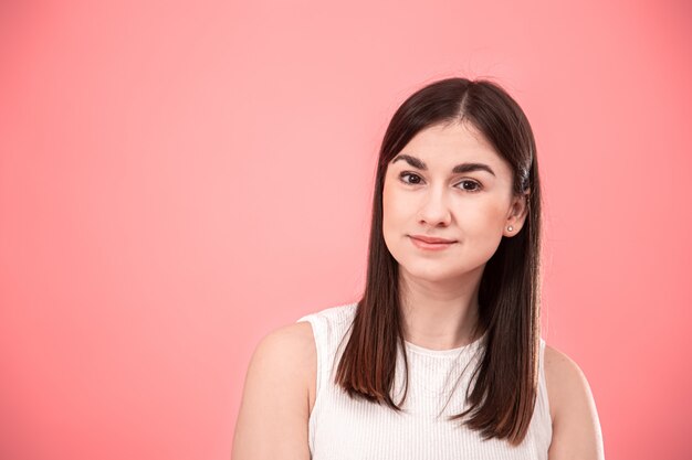 Retrato de una mujer joven que muestra emociones en rosa aislado.