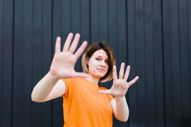 Retrato de una mujer joven que muestra gesto de parada contra la pared negra