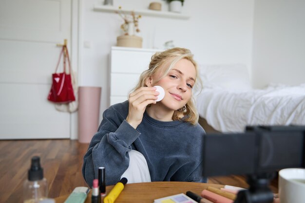 Retrato de una mujer joven que promueve un producto de belleza se aplica maquillaje frente a la cámara grabando video