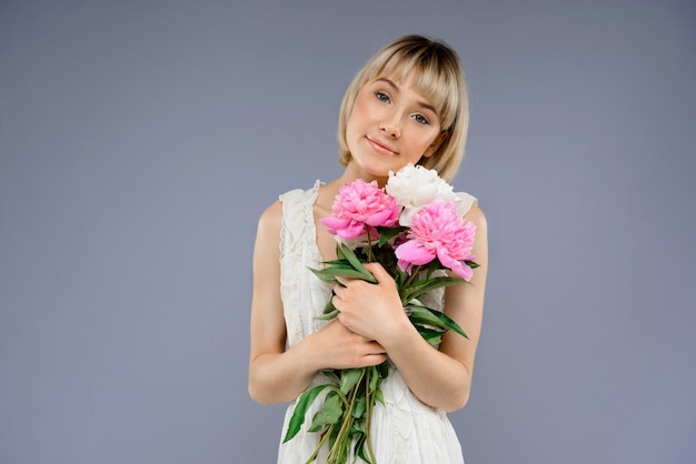 Retrato mujer joven con ramo de flores sobre centrico gris