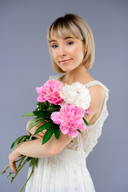 Retrato mujer joven con ramo de flores sobre centrico gris