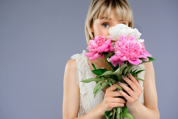 Retrato mujer joven con ramo de flores sobre centrico gris