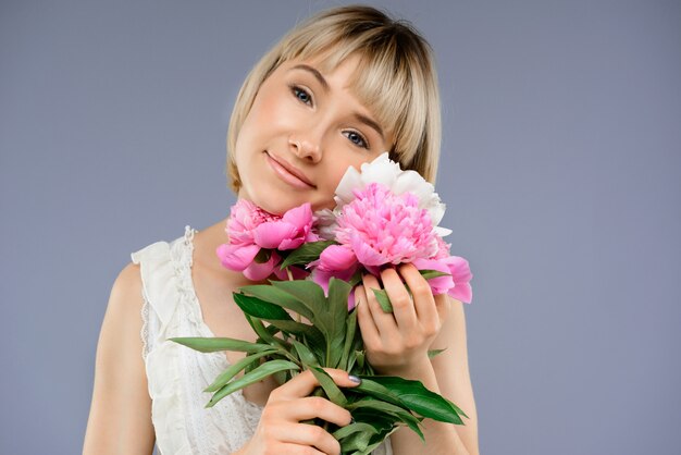 Retrato mujer joven con ramo de flores sobre centrico gris