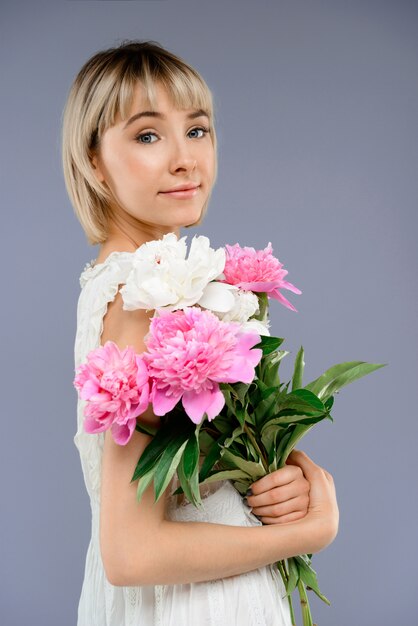 Retrato mujer joven con ramo de flores sobre centrico gris