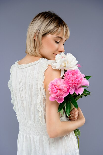 Retrato mujer joven con ramo de flores sobre centrico gris