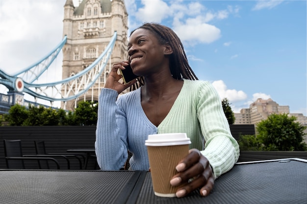 Retrato de mujer joven con rastas afro hablando por teléfono inteligente en la ciudad