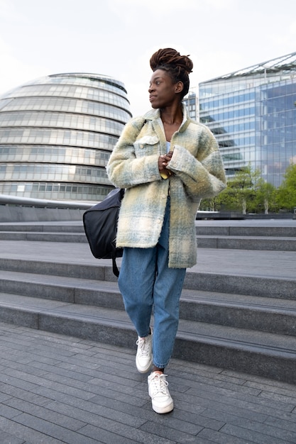 Foto gratuita retrato de mujer joven con rastas afro y mochila en la ciudad