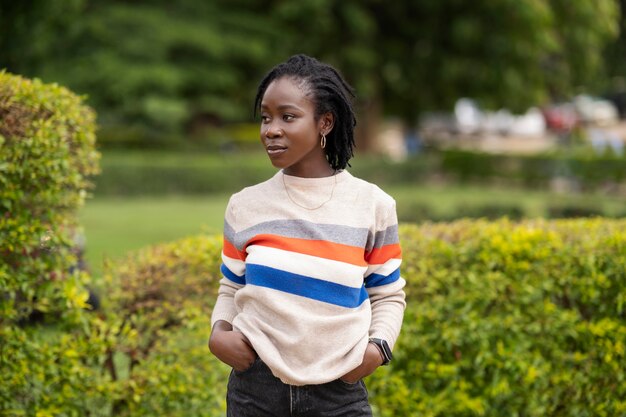 Retrato de mujer joven con rastas afro posando afuera