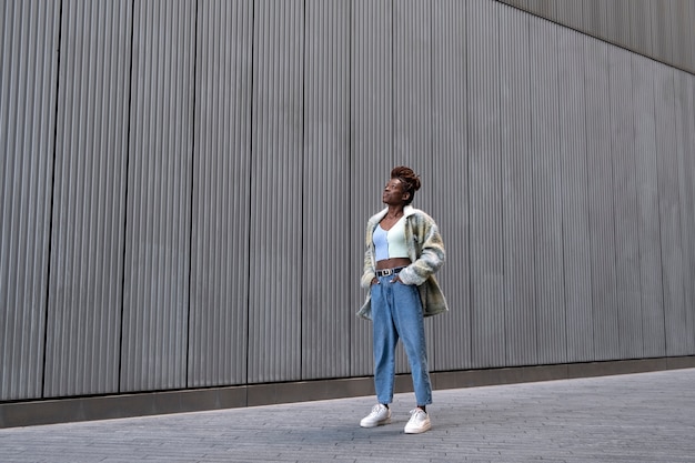 Retrato de mujer joven con rastas afro posando mientras está en la ciudad