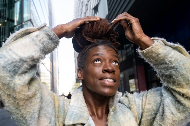 Retrato de mujer joven con rastas afro posando mientras está en la ciudad