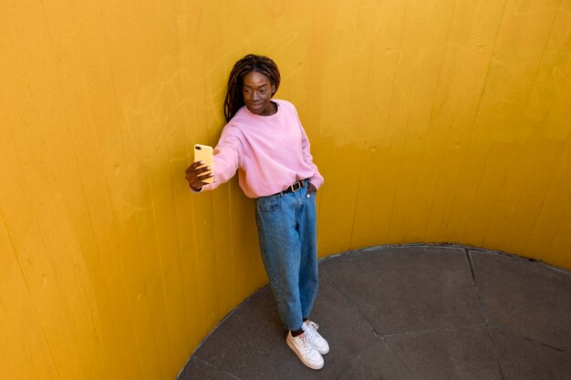 Retrato de mujer joven con rastas afro posando para selfies al aire libre