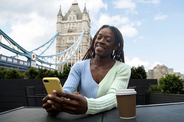 Retrato de mujer joven con rastas afro con smartphone en la ciudad