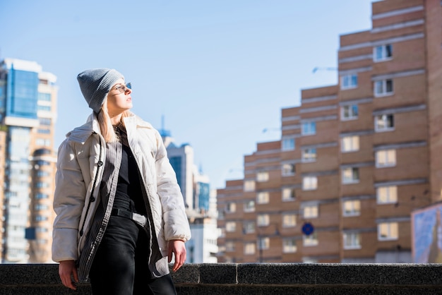 Retrato de una mujer joven rubia atractiva en la luz del sol que se opone al edificio