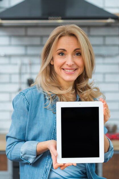 Retrato de una mujer joven rubia mostrando tableta digital