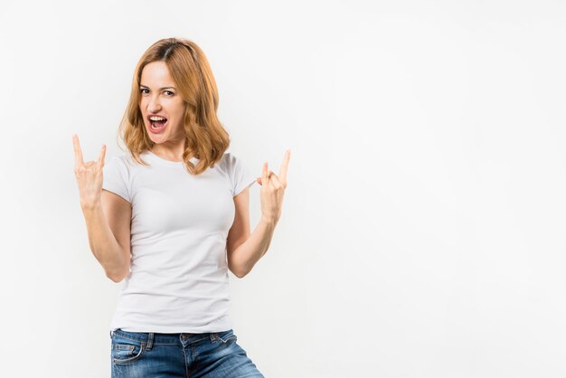 Retrato de una mujer joven rubia que muestra gesto de rock and roll contra el fondo blanco